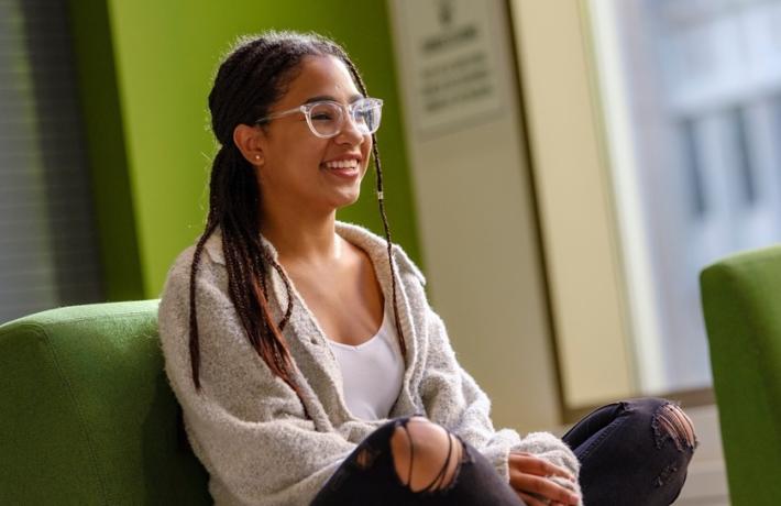 Photo of student with legs crossed smiling