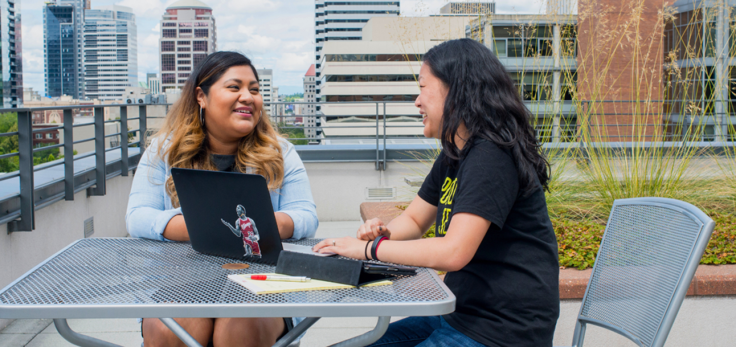 Student and staff member sitting at table on the PSU ASRC terrace.