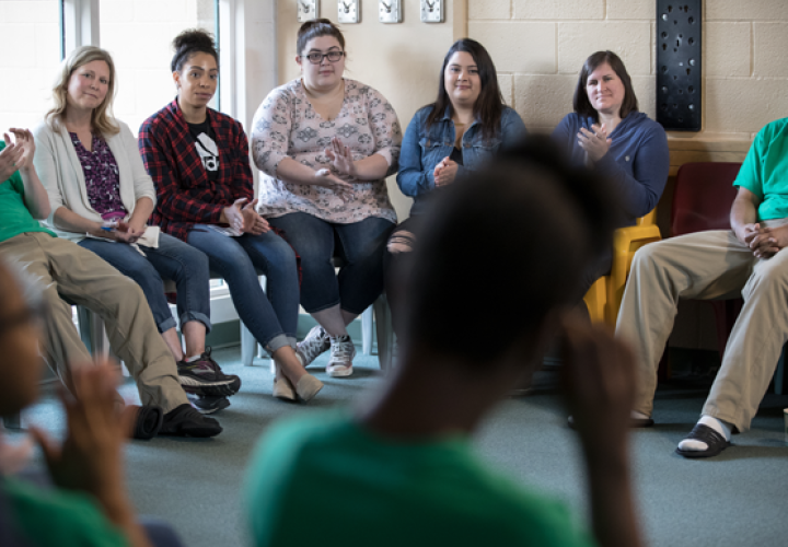Photo of a group of people sitting together in a circle and clapping