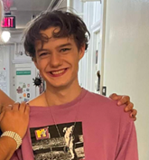 Clover is wearing a pink MTV shirt and have short curly hair