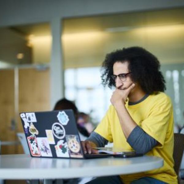 Guy with brown hair and glasses looking at a computer