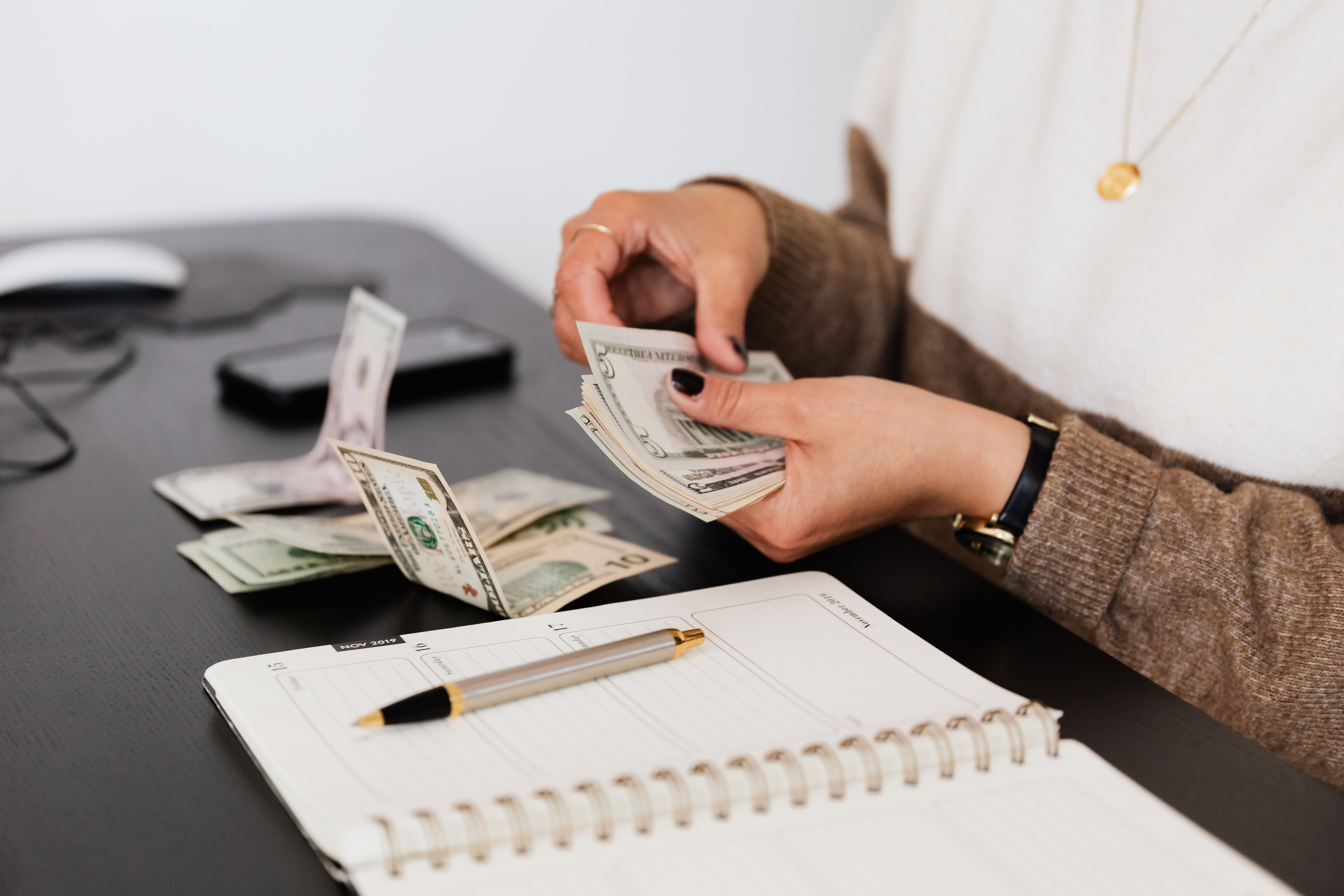 Payroll clerk counting money while sitting at a table