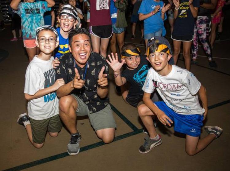 Student with children giving the thumbs up gesture