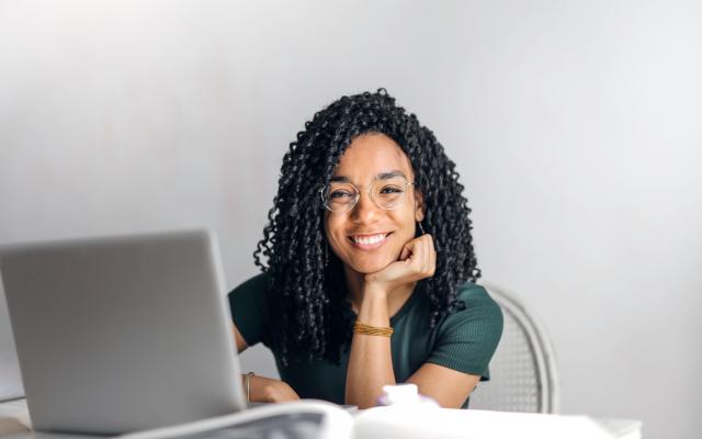 Smiling woman sitting at table with laptop