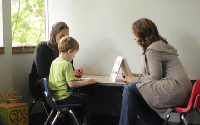 Two student research assistants conduct a vocabulary assessment with a preschooler.