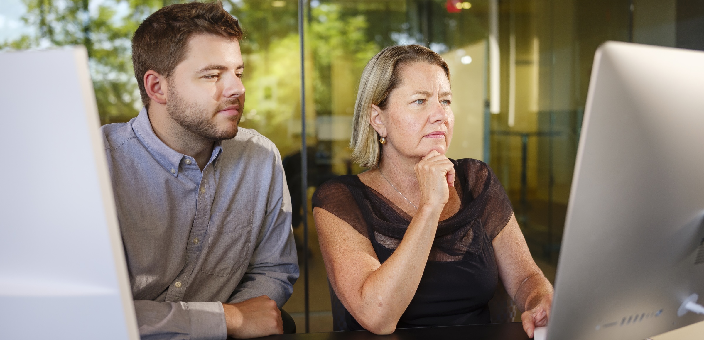 Two people looking at an iMac computer screen.