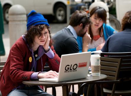 Student sitting in front of a laptop at a small table with face resting on one hand
