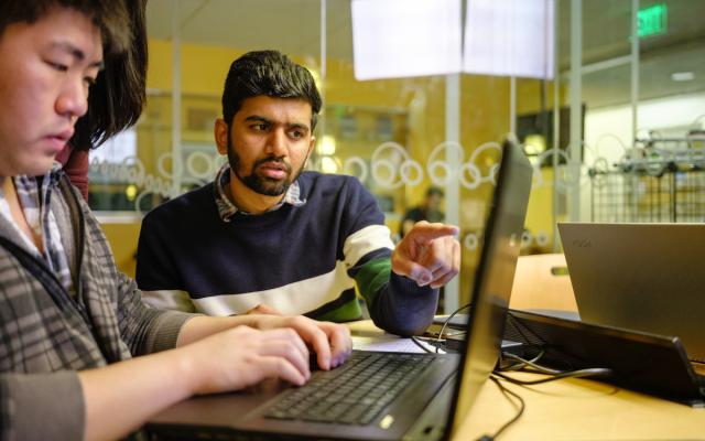 Two men sitting at a laptop studying.