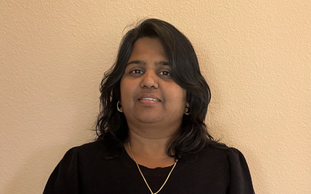 Female-identified person with medium-length black hair, wearing a black shirt and gold necklace.