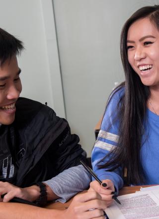 A tutor and student laughing and smiling while working