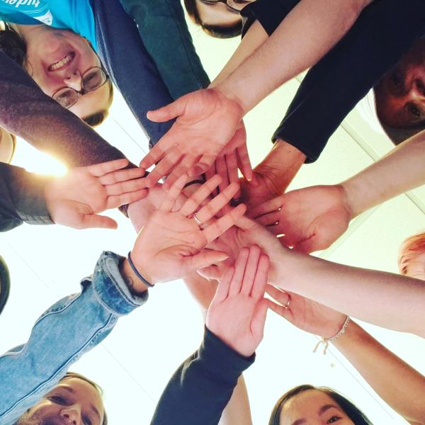 Many students in a circle with their hands outstretched and stacked on top of each other