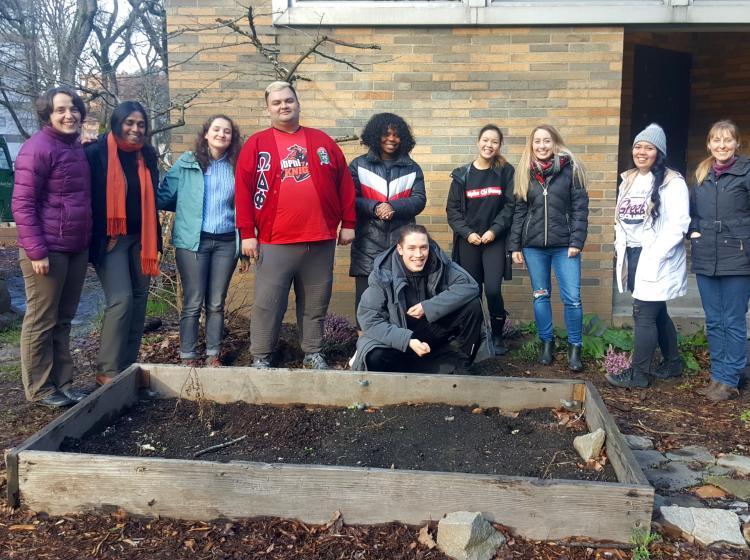 Group of students and staff stand behind a freshly weeded garden box next to Smith Memorial Student Union