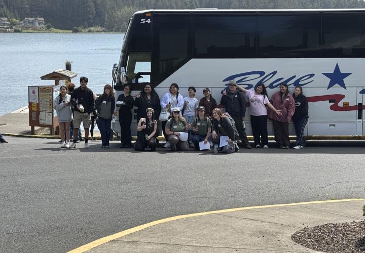 people standing by bus next to body of water
