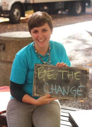 Girl holding up sign that says 'be the change'