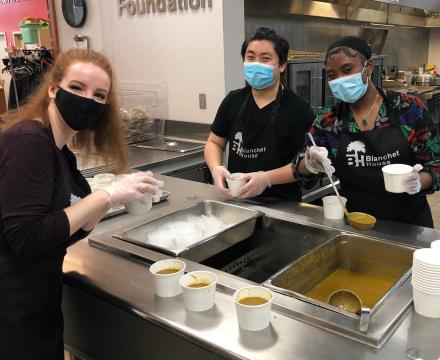 Three students wear masks while serving up food at Blanchet House
