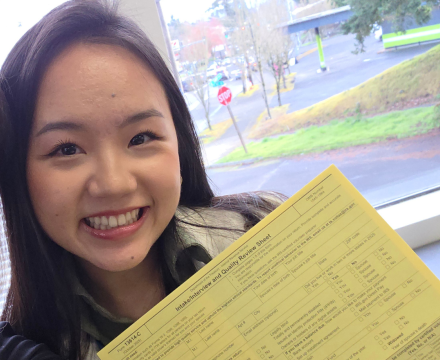 girl holding yello paper smiling