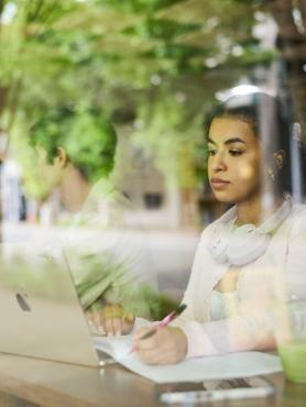 A student working on a laptop in a coffee shop on campus