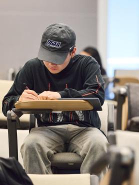 A student taking notes at a desk in a PSU classroom