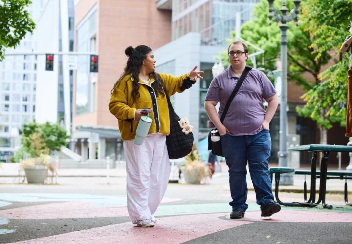 Two students conversing while walking through the electric avenue block on campus
