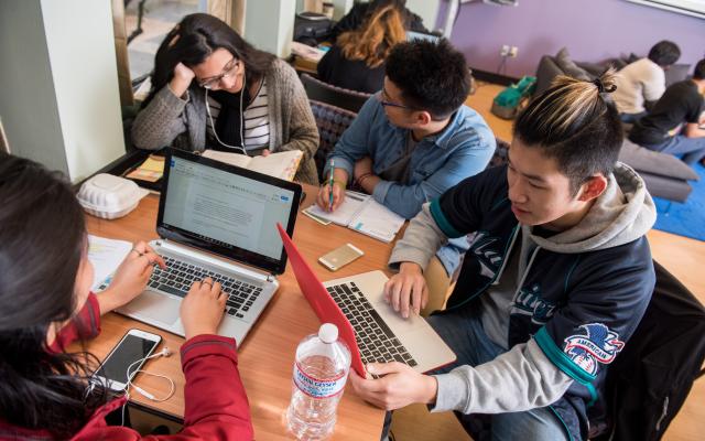 Group of four students working at a table together