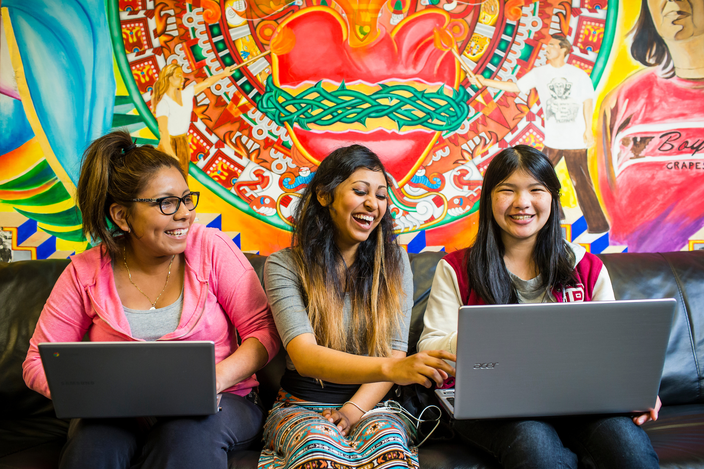 Students laughing around a laptop