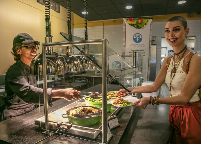 PSU student in the dining hall putting food onto a plate.