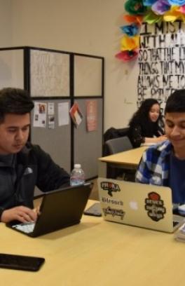 La Casa Latina Student Center with students on computers at a table.