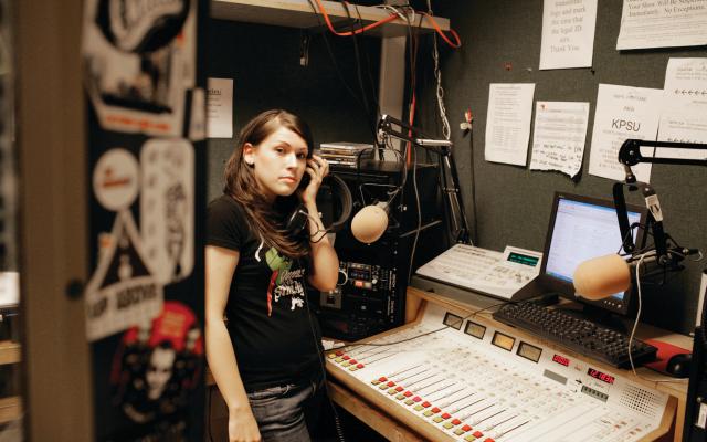 Student with a headphone to their ear in the media room.