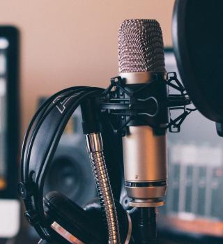 Professional podcasting setup with headphones, a computer, and a microphone