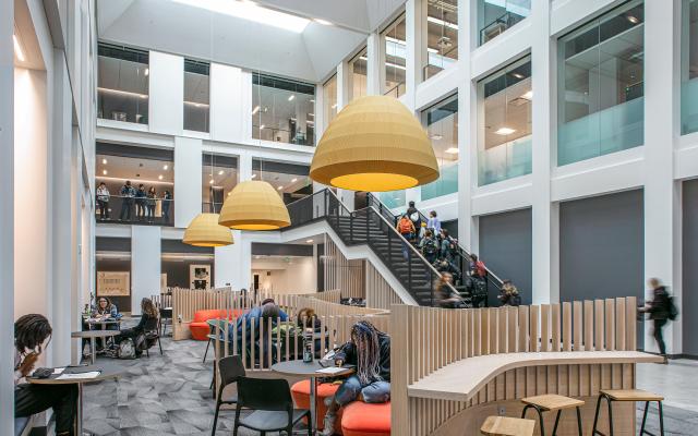 far away photo that shows students sitting at tables and students walking upstairs