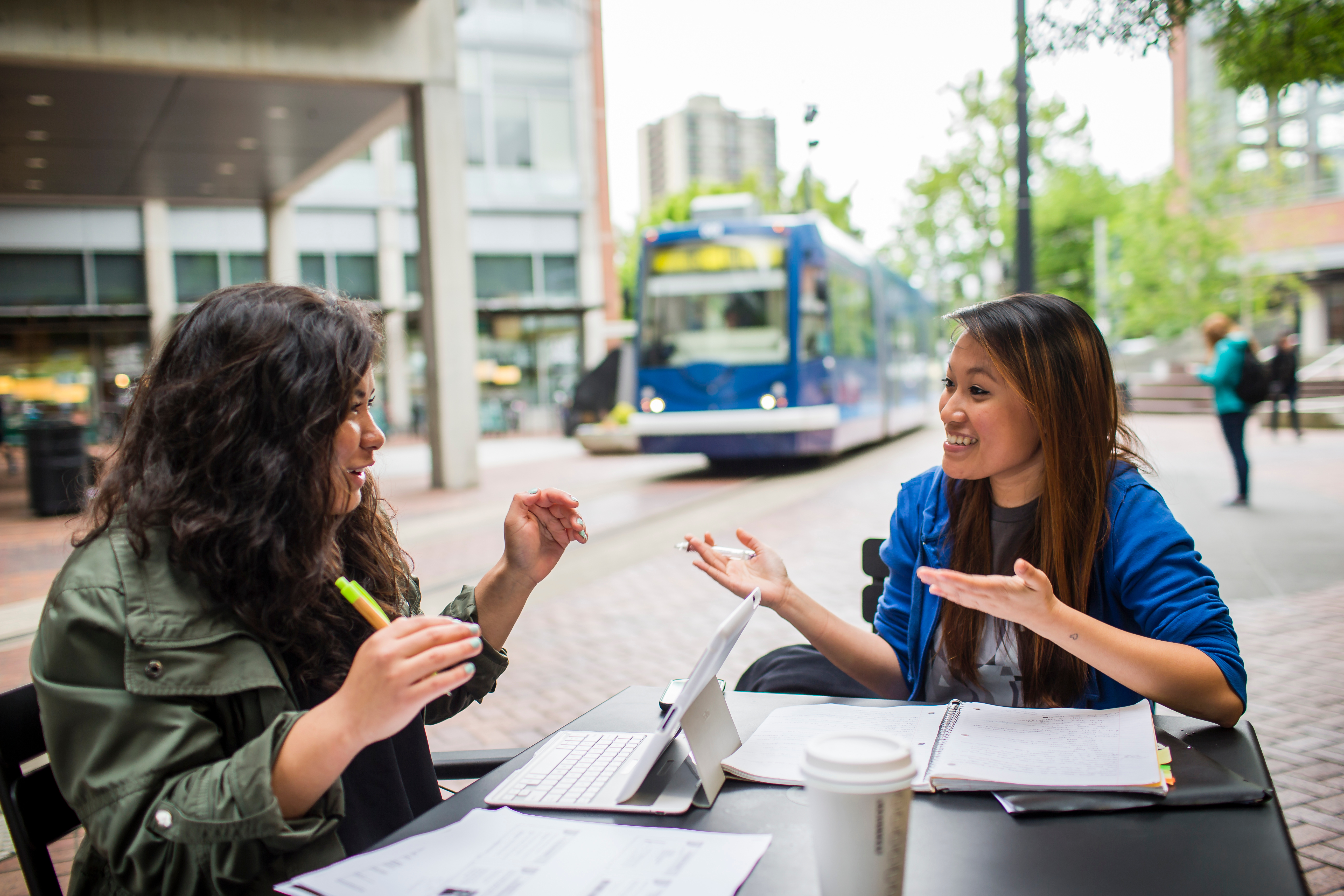 two students studying with streetcar in background