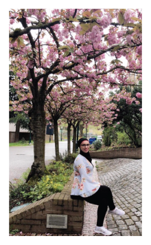 May Mousa sitting under a blooming cherry tree