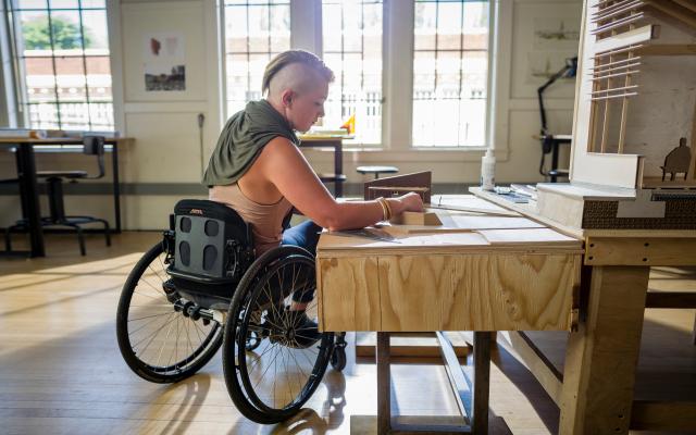 person in wheelchair working on a project on a table