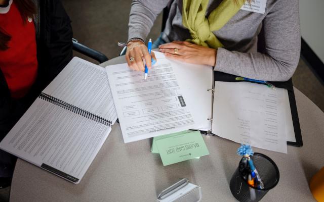 person pointing to a sheet of paper with text on it