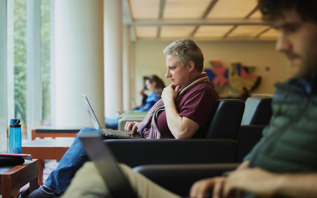 person sitting in an armchair using a laptop