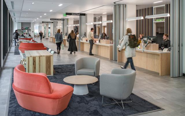 People walking through a lobby in front of a line of service desks