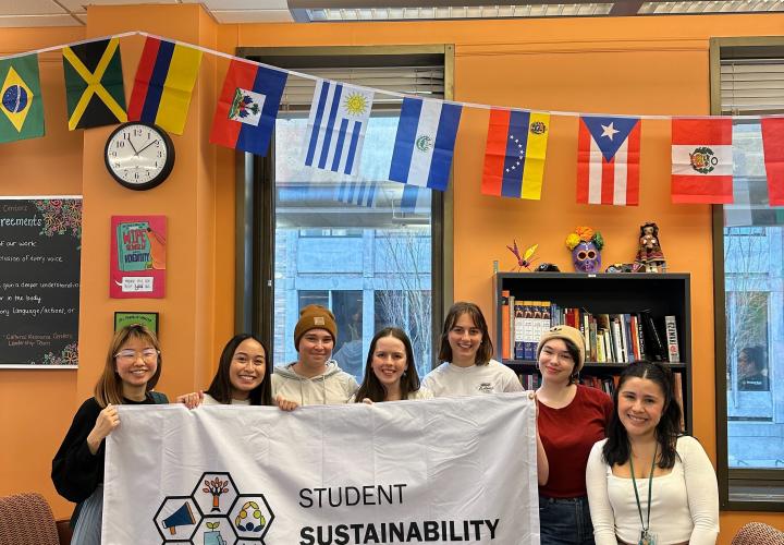 Seven students are shown holding a white flag that reads Student Sustainability Center with a honeycomb logo.