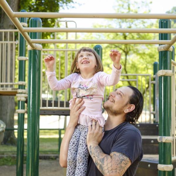 A smiling Father and Child in the Park Block Playground.