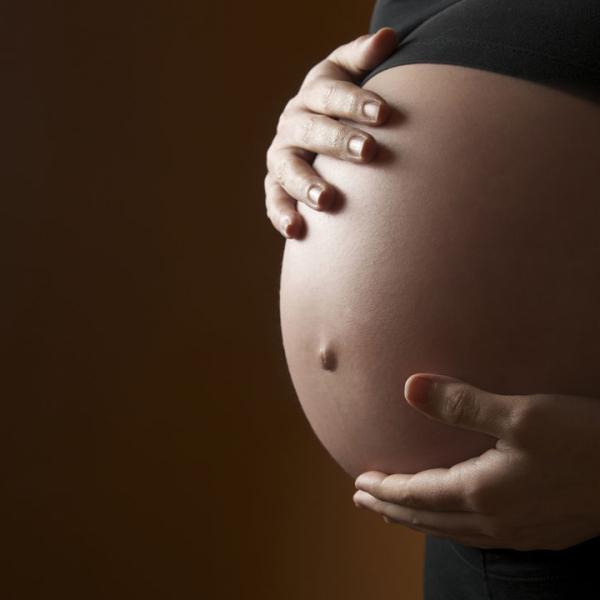 image of pregnant person with hands around their belly 