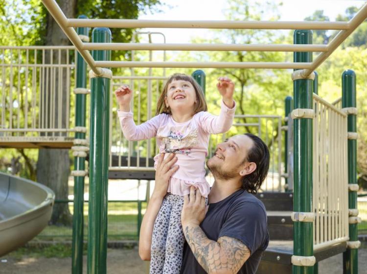 A smiling Father and Child in the Park Block Playground.