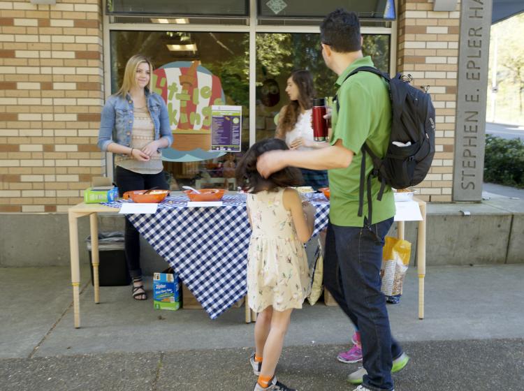 Booth set up outside Little Vikings Childcare, a father and his daughter are walking past.