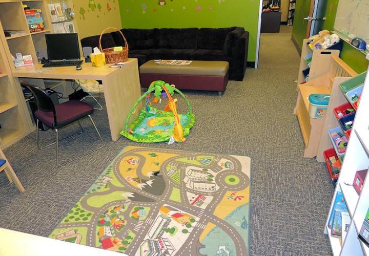 Our resource room equipped with a computer with desk, children's toys, and a couch.