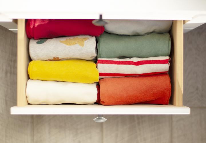 A drawer pulled open with folded clothing inside.