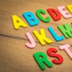 Letter toys arranged in alphabetical order on a wooden surface.