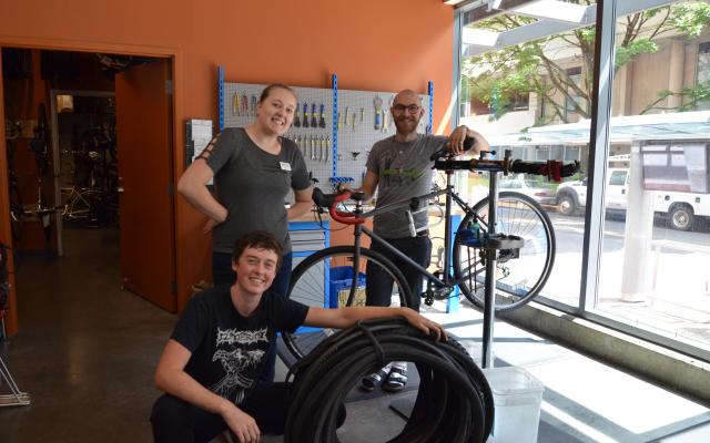 3 people standing with a bike and bike tires