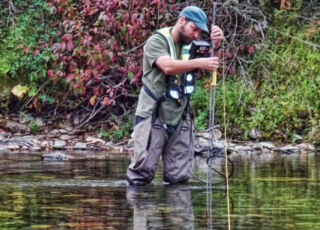 A hydrologic technician from the USGS Idaho Water Science Center measures streamflow in St Joe River at red Ives, ID