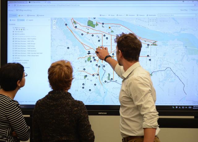 Three people looking at a map view of Portland Oregon