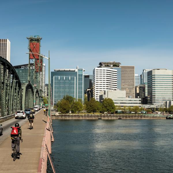 Biker on Hawthorne Bridge with Portland cityscape and Willamette River