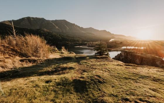 photo of columbia river running through landforms with sunshine on the far right of the image