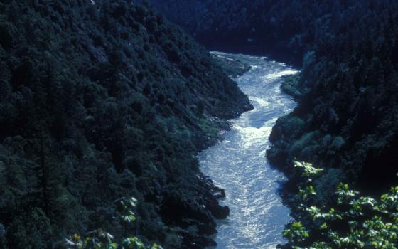The Klamath River flows in a canyon below steep rocky and forested slopes.